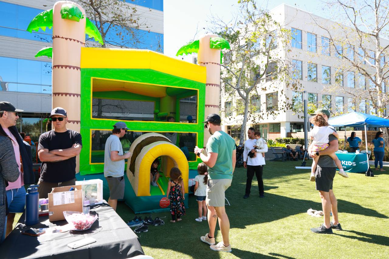 Families and kids gathered around the Jungle Jamboree bounce house at the FIT4MOM Grand Reopening